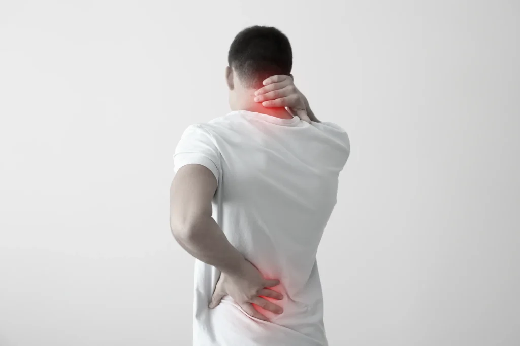 A man with an injury on his neck and back that he his holding.