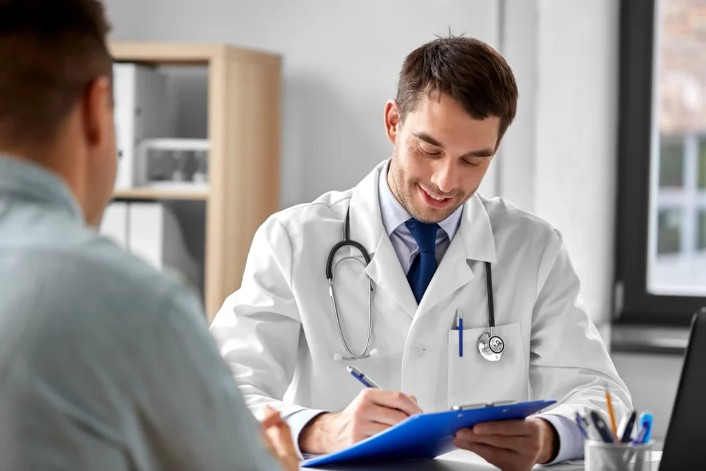 Smiling doctor taking notes while discussing car accident injuries with patient.