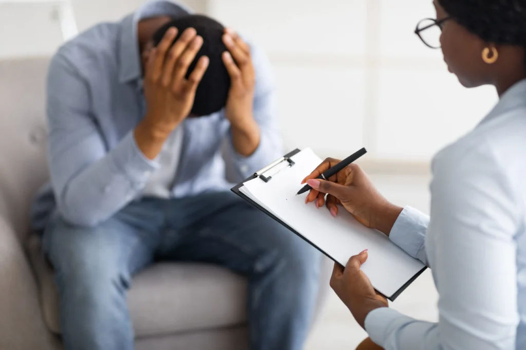 A man with his head in his hands while speaking with his doctor.