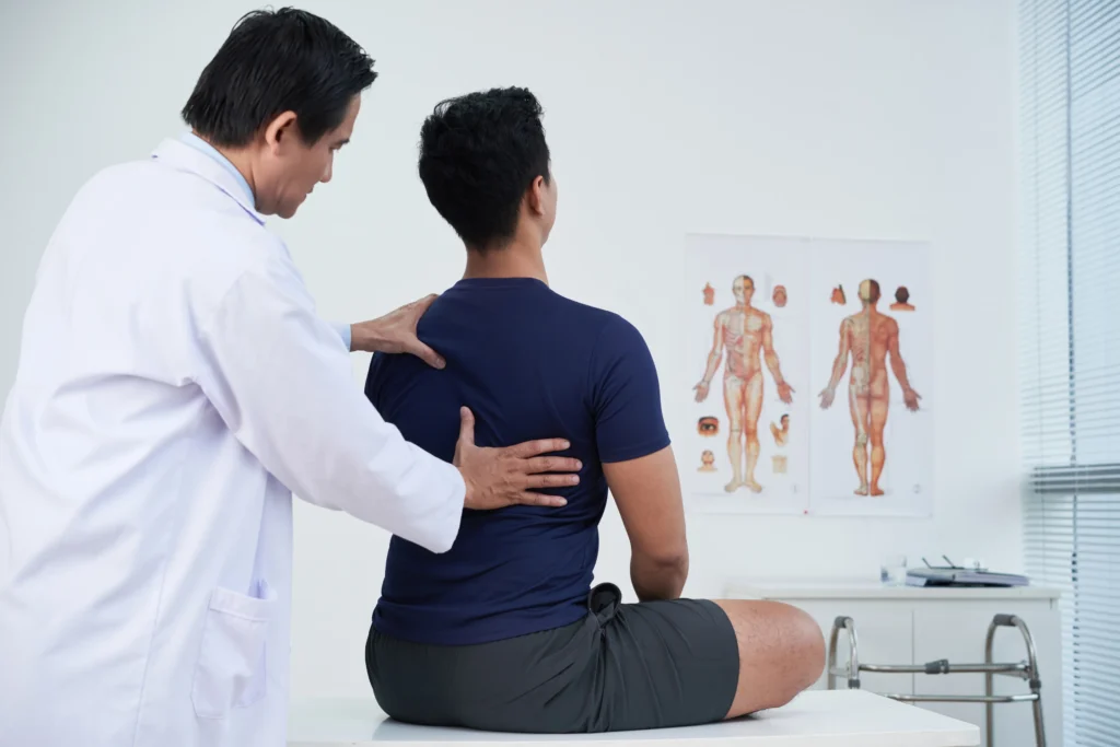 Doctor examining patient’s spine during back pain appointment in Oklahoma City.