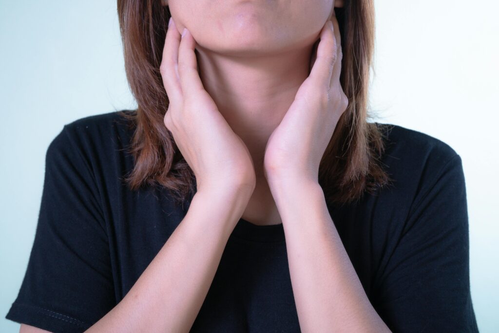 person feeling their jaw and neck in pain