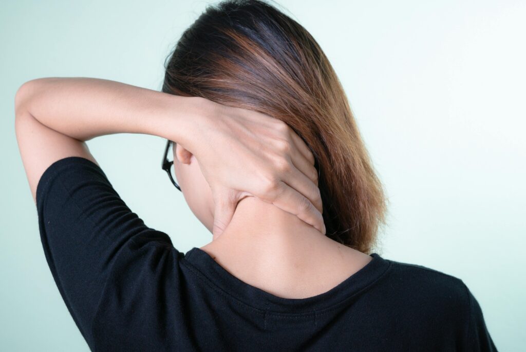 woman grabbing the back of her neck in pain