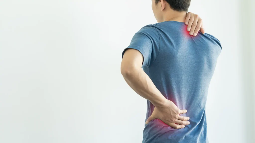 Man holding his upper back and lower back in pain, with red highlights indicating areas of discomfort, representing interventional pain management treatment areas.